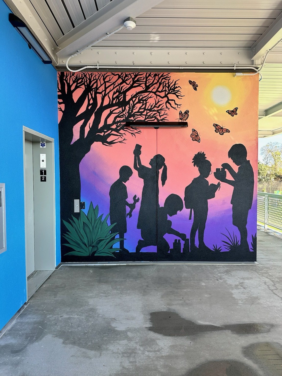 Sunset mural with silhouettes beneath a tree