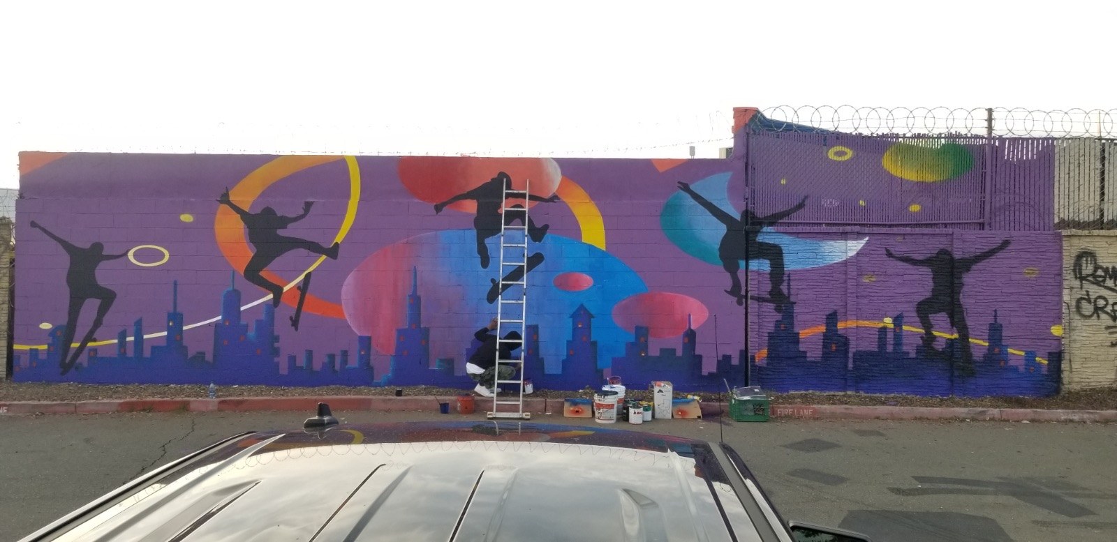 Wide purple mural featuring figures and colorful shapes