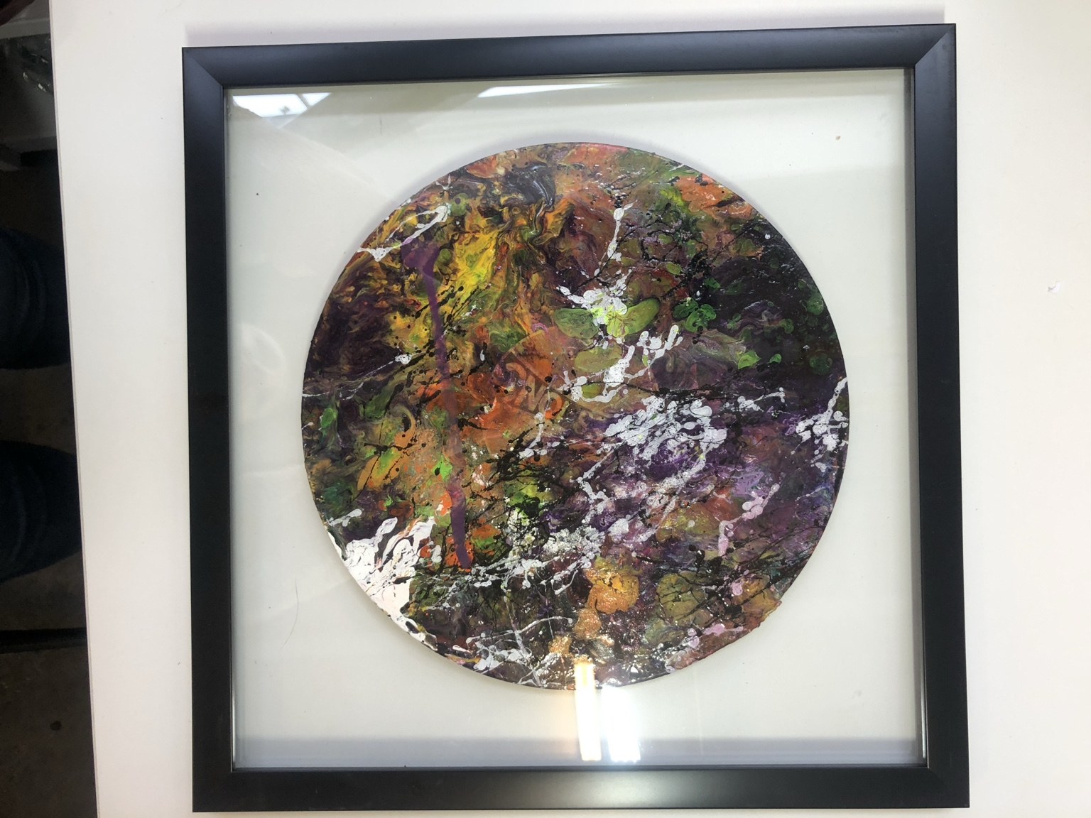 Framed circular record artwork with layered multicolored paint