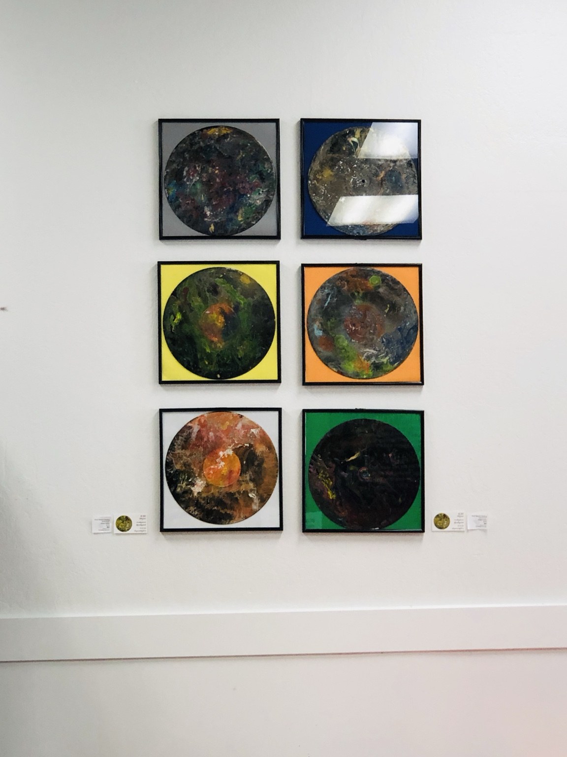 Six circular record artworks displayed together on a gallery wall
